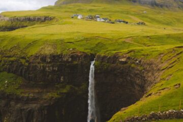 man standing on cliff watching punch bowl waterfalls